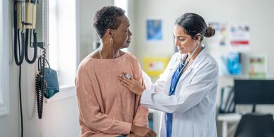 Doctor using stethoscope to check patient's heartbeat in clinic.
