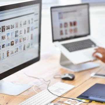 A woman working on a digital tablet and computer screens.