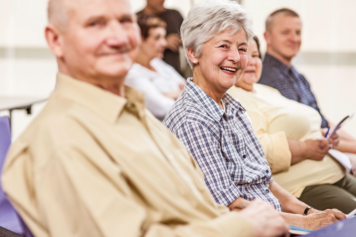 Happy seniors sitting in a row, smiling and engaging in an activity.