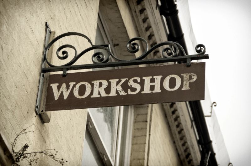A workshop sign on a wrought iron bracket.