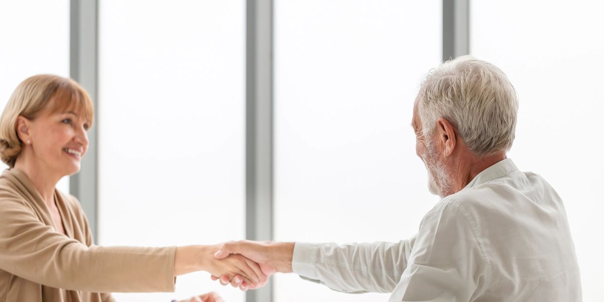 Two mature professionals shaking hands, smiling in a bright office.eldercare nursing CuraVia Concierge Nursing
healthcare journey support
nurse-led patient advocacy