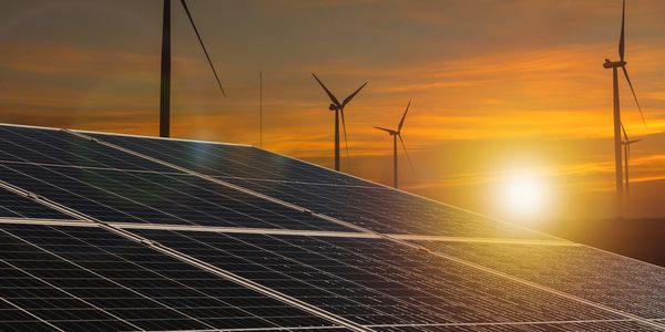 Solar panels and wind turbines harness renewable energy at sunset.