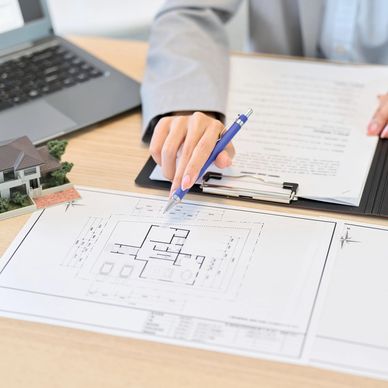 Person reviewing house plans and pointing with a pen on architectural blueprints.