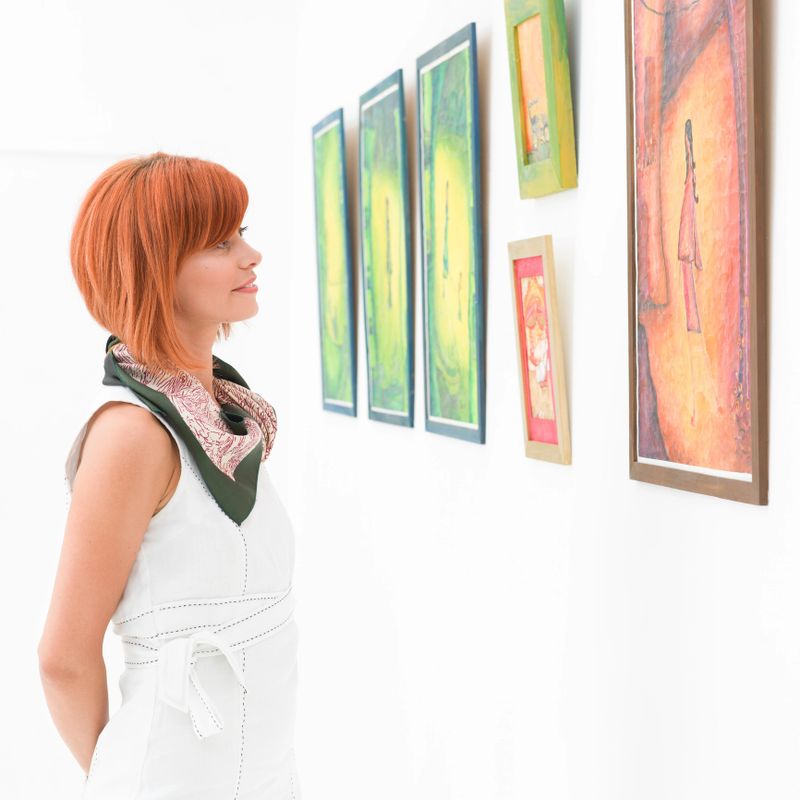 side view of young attractive redhead woman standing in an art gallery contemplating an artwork