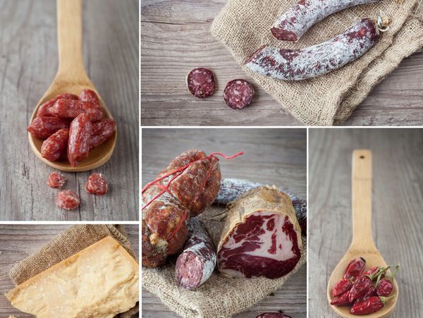Assortment of cured meats, cheese, and chili peppers on rustic wooden surfaces.