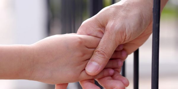 Adult and child holding hands gently.