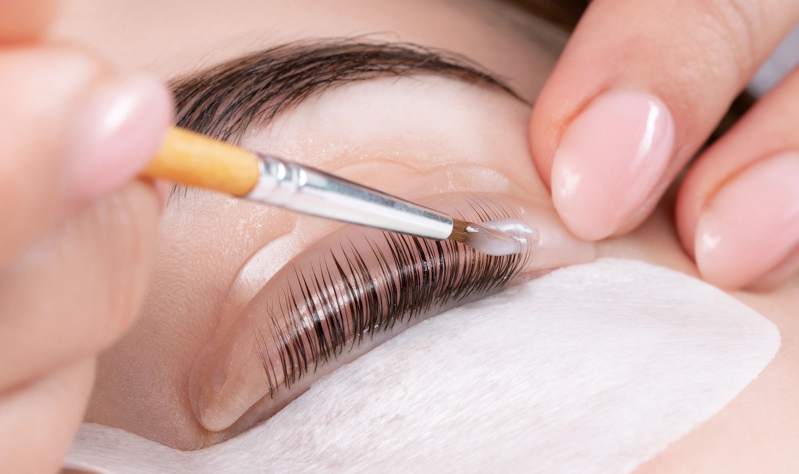 Applying eyelash extensions with a brush.