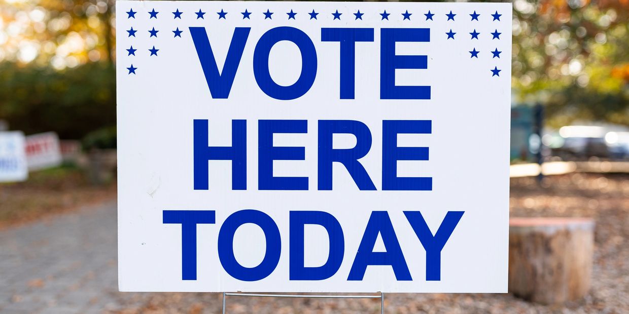 Sign reading 'VOTE HERE TODAY' in blue letters with stars on top.