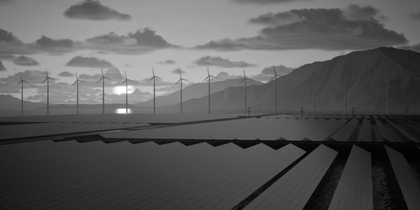 Solar panels and wind turbines at sunset in a mountainous landscape.