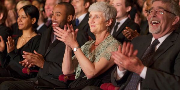 A diverse audience applauding at a formal event.