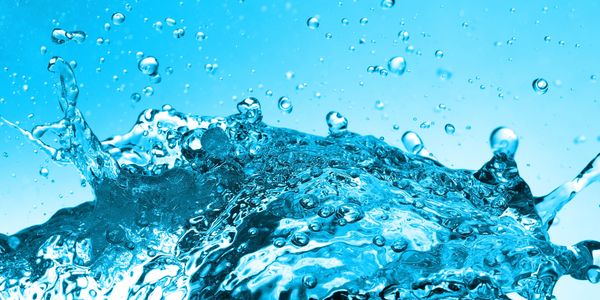 Close-up of water splashing with bubbles against a blue background.