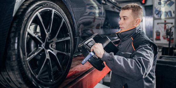 Mechanic inspecting a car wheel in a workshop.