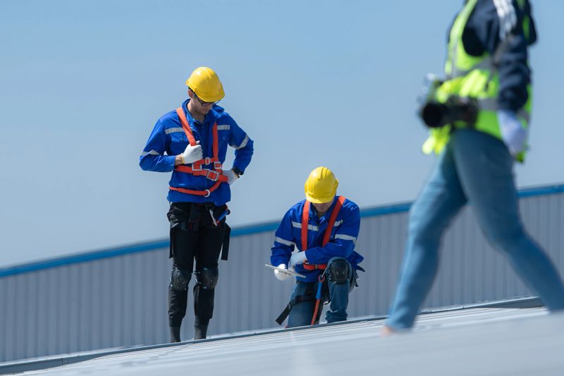 Both of technicians is installing solar panels on the roof of the warehouse to change solar energy into electrical energy for use in factories.