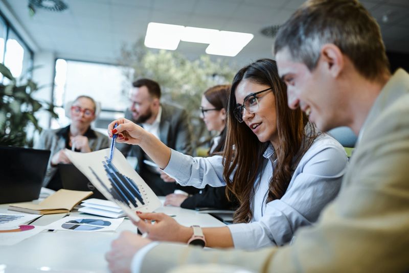Female Financial Manager Explaining Profit Spikes To Male Project Manager During Meeting
