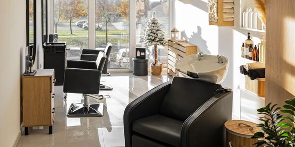 Well-lit hair salon with black chairs and a small Christmas tree.