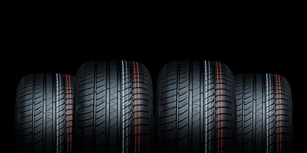Four new car tires with colorful stripes on a black background.