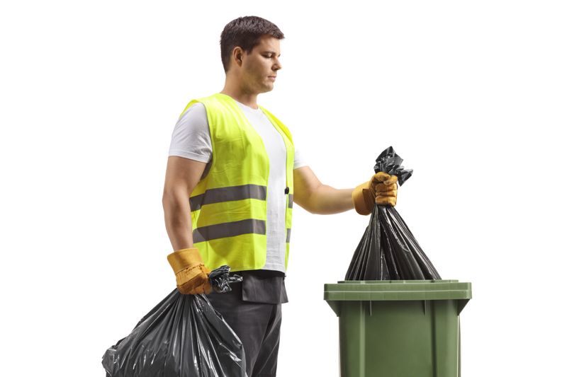 Waste collector taking a bag from a bin isolated on white background