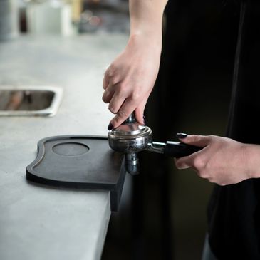 Person tamping coffee grounds with a tamper.