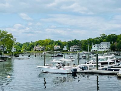 Boats on the water in Darien, CT with homes in between trees in the distance