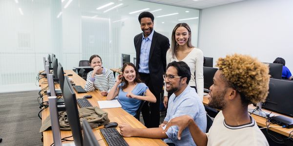 Diverse team collaborating happily around computer monitors.