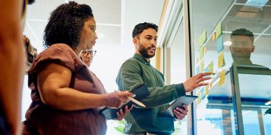 Team discussion with sticky notes on a glass board.