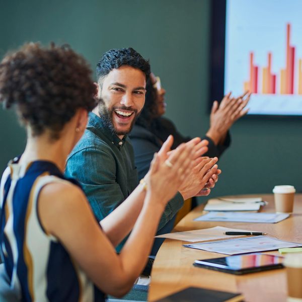 Colleagues clapping during a meeting with a positive atmosphere.