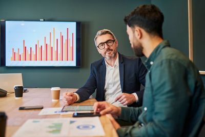 Two men discussing data charts in a business meeting room.