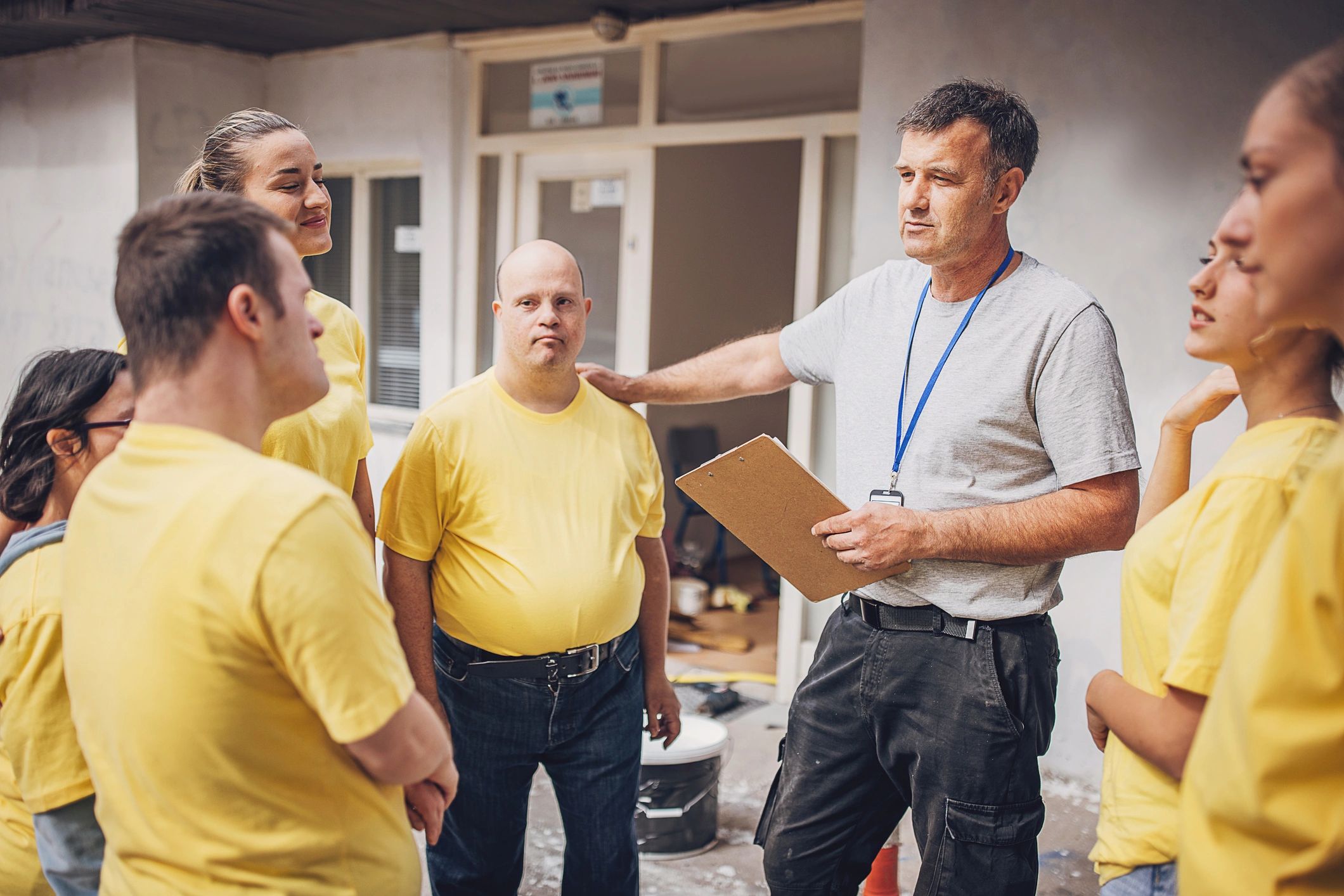 Senior man coaching a group wearing yellow t-shirts.
