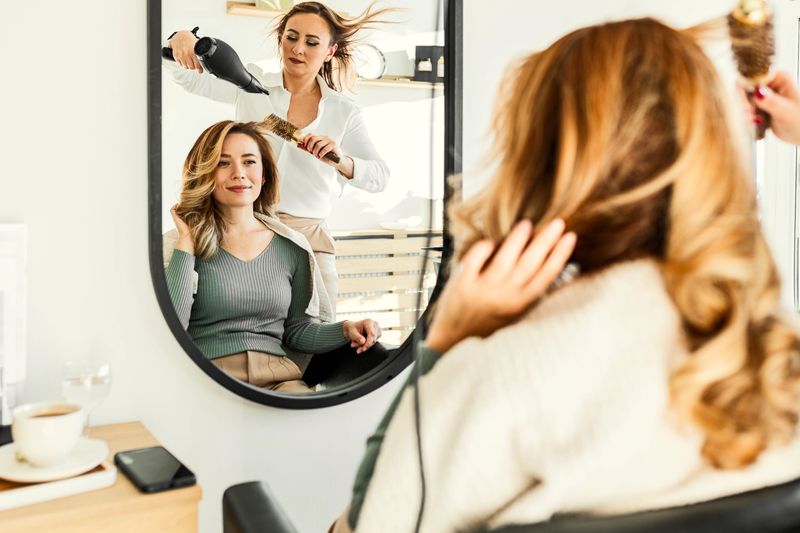 Hairdresser drying the hair of a young woman in her hair salon