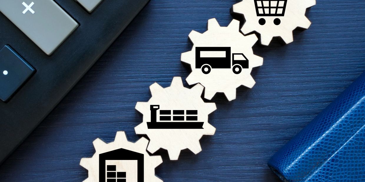 Wooden cogs with icons of warehouse, ship, truck, and shopping cart.