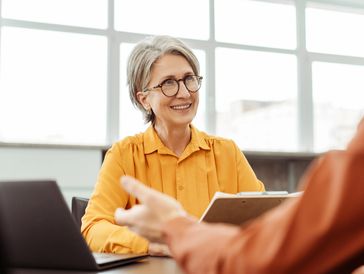 Smiling woman in glasses listening attentively during a conversation.