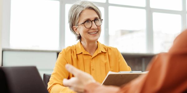 Smiling older woman in glasses listening attentively.