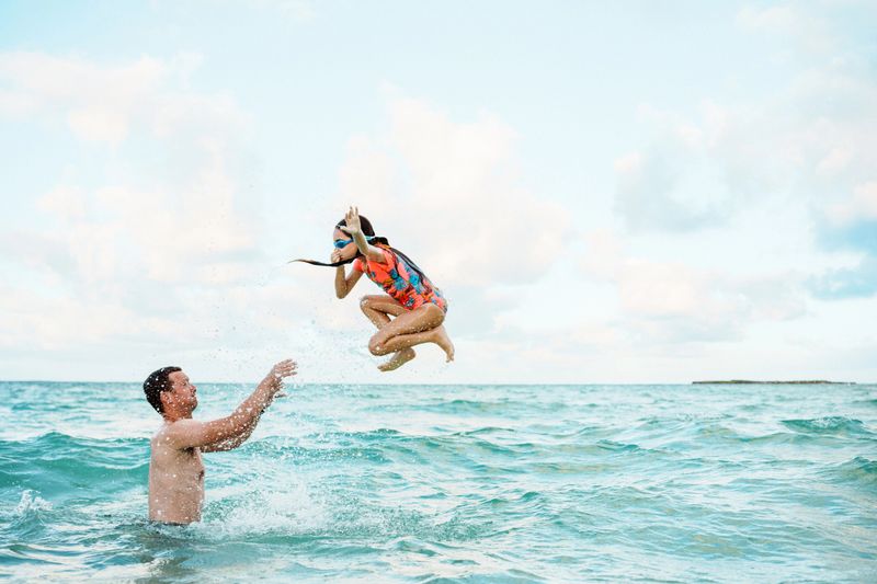 A joyful child laughing during a playful outdoor photoshoot at the beach.