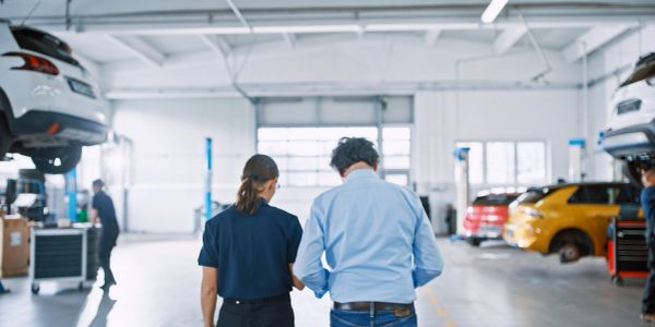 Two people walking in an auto repair garage.