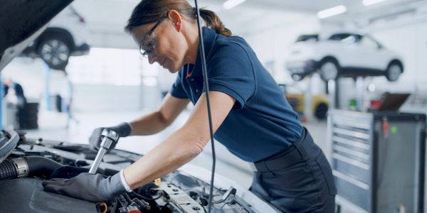 Female mechanic working on a car engine.
