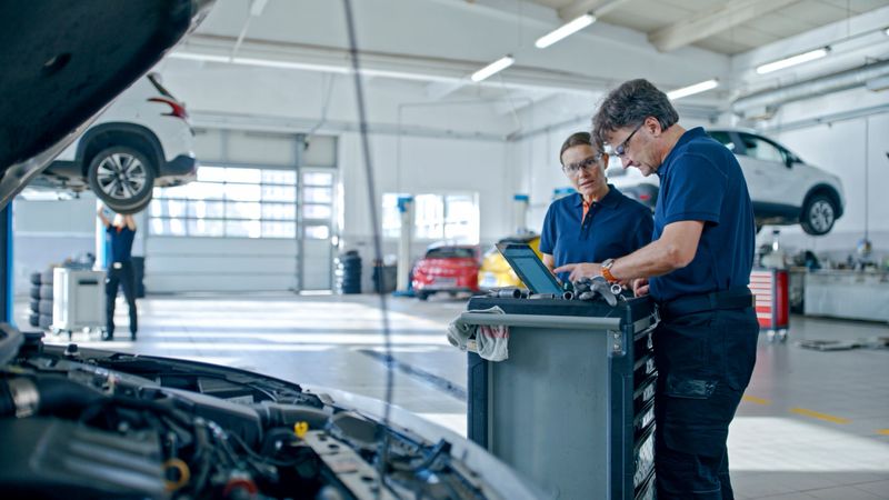 Manager And Mechanic Conducting A Thorough Inspection Of A Car Engine Using Laptop In The Auto Repair Shop