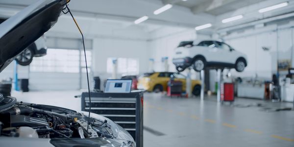 Car engine being checked in a spacious auto repair shop.