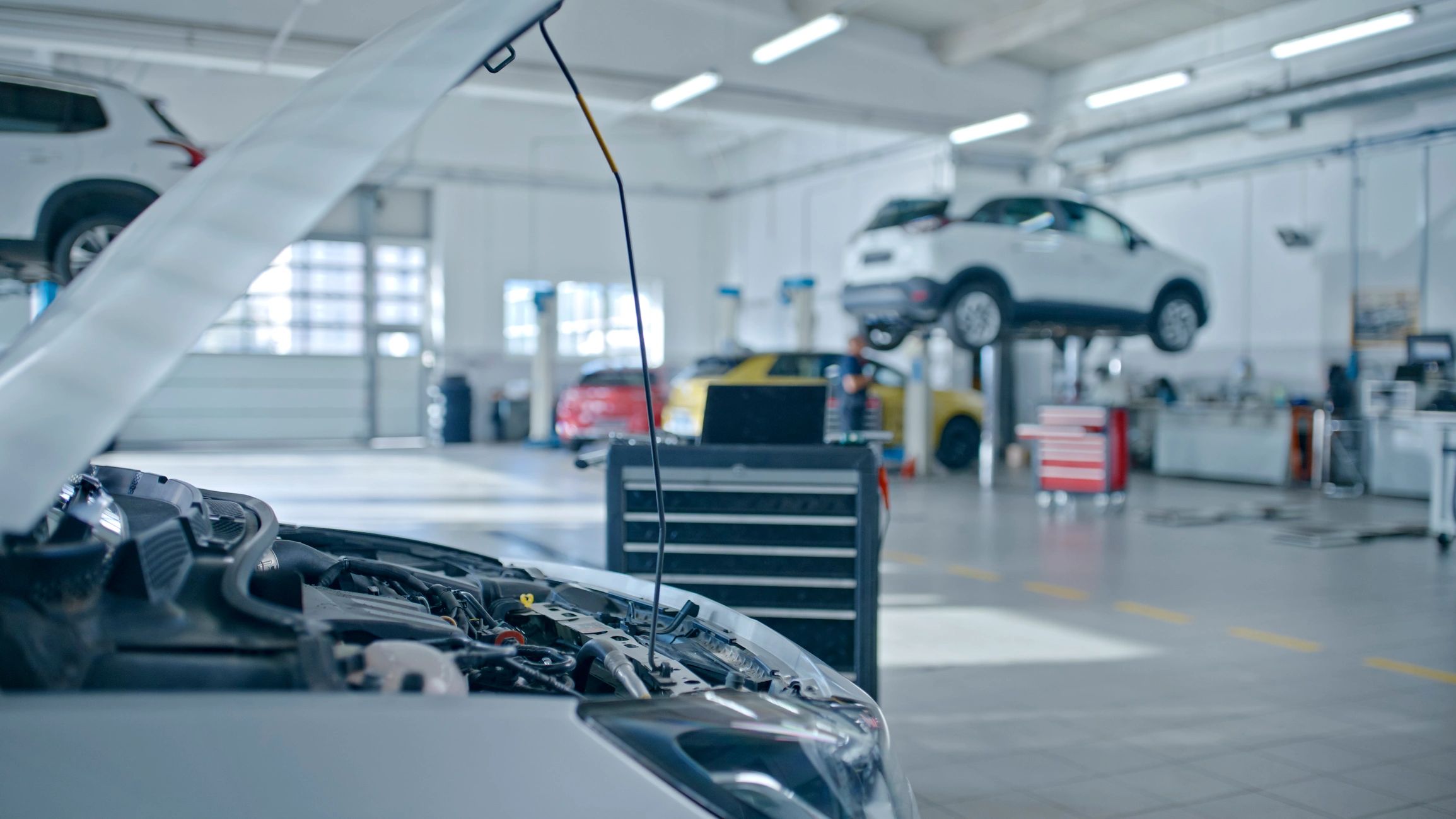 Car engine being inspected in a bright auto repair shop.