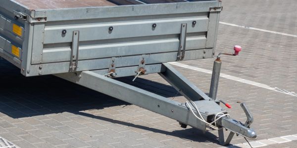 Close-up of a trailer hitch and pallet truck parked on pavement.