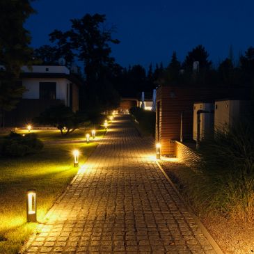 Well-lit pathway at night with garden lights.