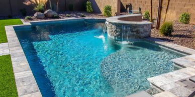 Modern backyard pool with waterfall and clear blue water.