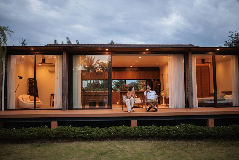 A smiling couple is enjoying a tranquil moment on the balcony in front of the house at dusk.
