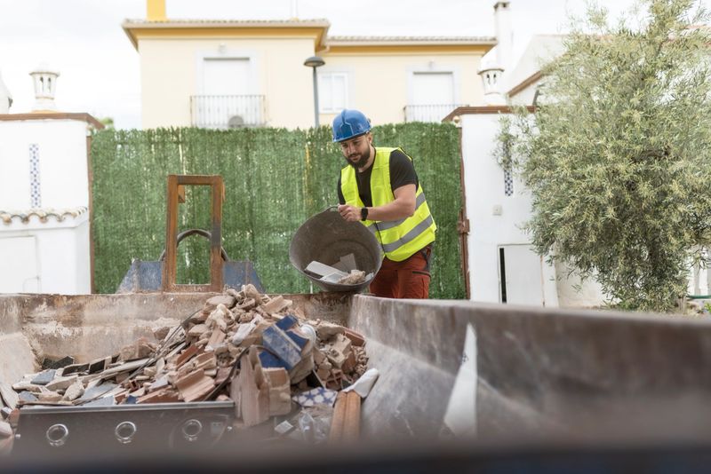 construction worker throws debris into a container , working in reforms