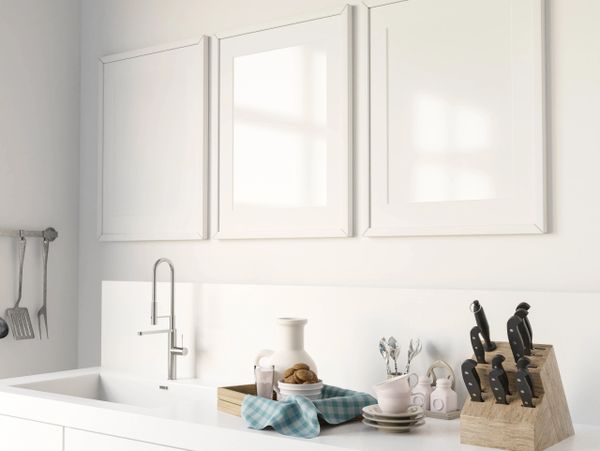 Bright white kitchen countertop with modern faucet and organized utensils.
