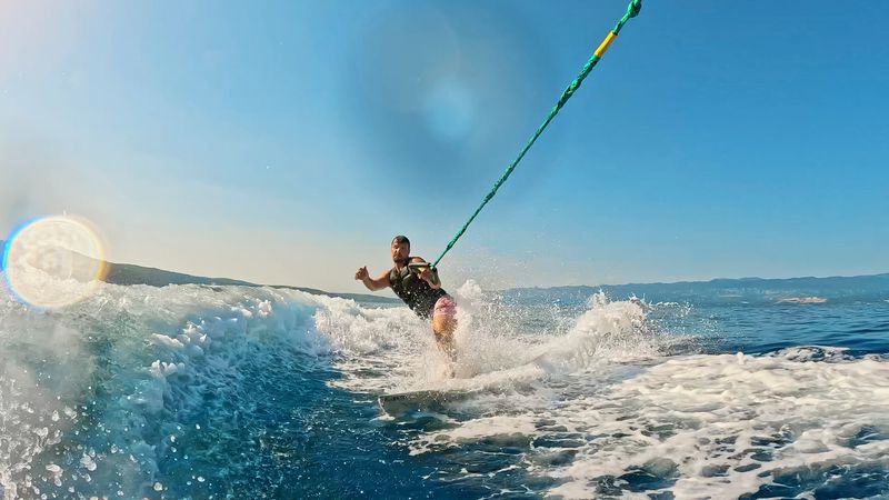 Man Holding a Rope,Experiencing the Excitement of Wakeboarding in the Sea,Creating a Spectacular and Thrilling Scene of Adventure and Fun On a Bright Sunny Day with a Clear Blue Sky.