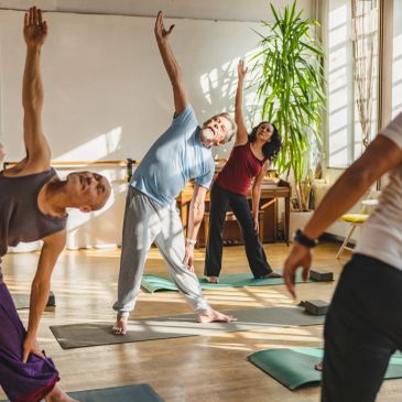Group yoga session with diverse participants stretching indoors.