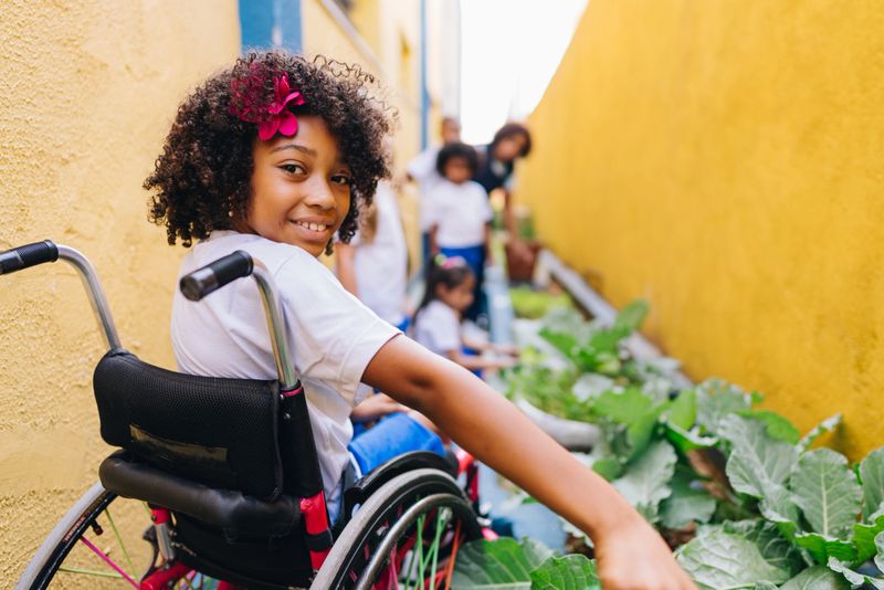 Portrait of a girl student using wheelchair its doing gardening at school