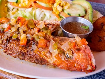Grilled whole fish with vegetables and sauce.