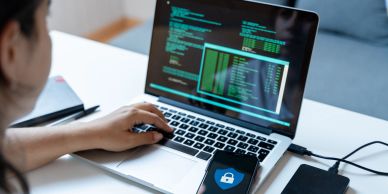 Person working on cyber security with a laptop and phone.