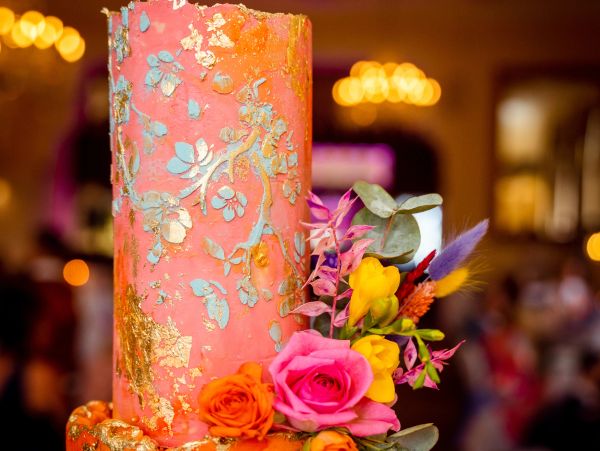 Elegant orange and pink cake with floral decorations.